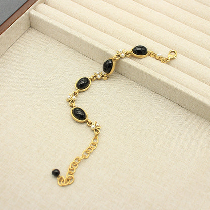 Vintage oval black glass necklace with gold chain and small butterfly charm accents