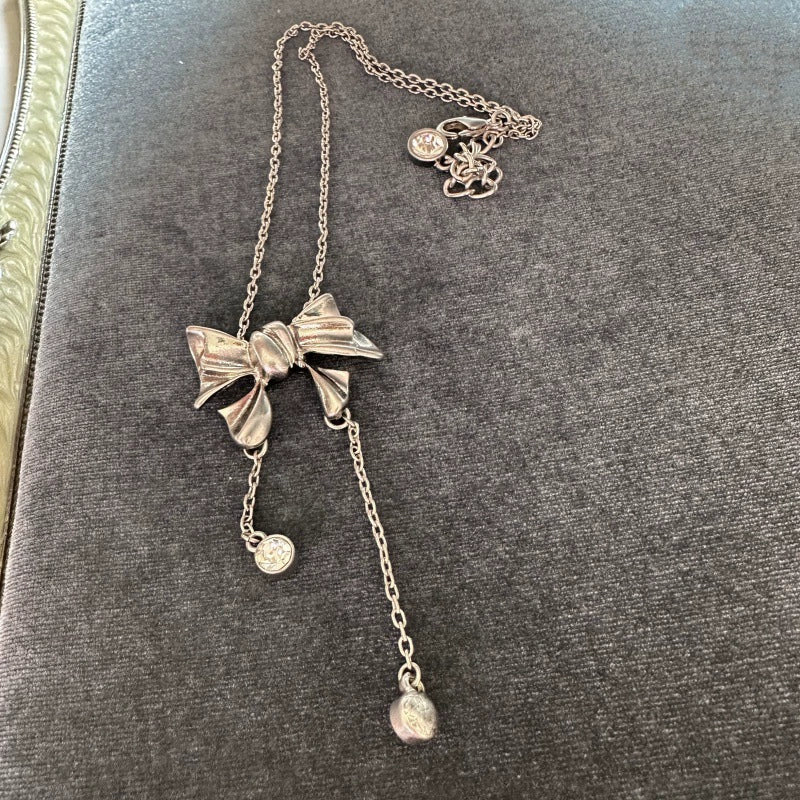 Metal-tone bow crystal tassel necklace with three dangling round stones