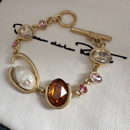 Gold-tone crystal and pearl O-ring bracelet with brown oval center stone and pink drops