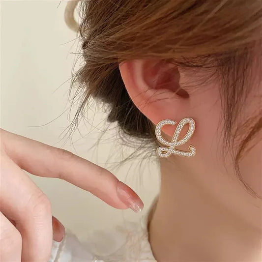 Geometric pearl-encrusted earrings on ear, white gold tone with pearl details