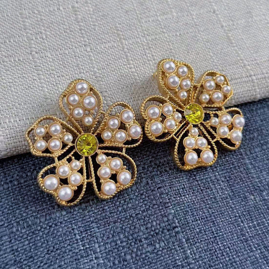 Pair of floral stud earrings with white pearls, gold-tone openwork, and yellow center stones