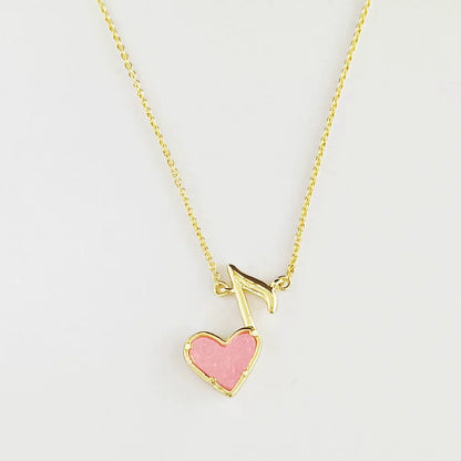 Gold-tone pendant necklace with pink heart and music note drop on chain