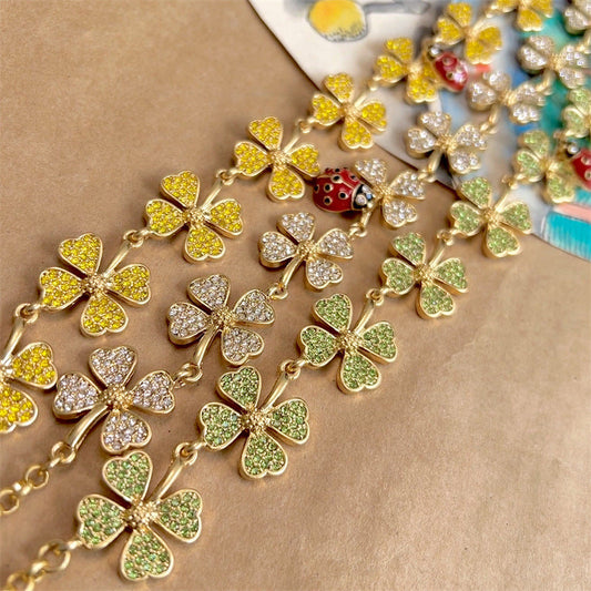 Gold-tone crystal clover necklace with ladybug charm, scattered clover elements close-up