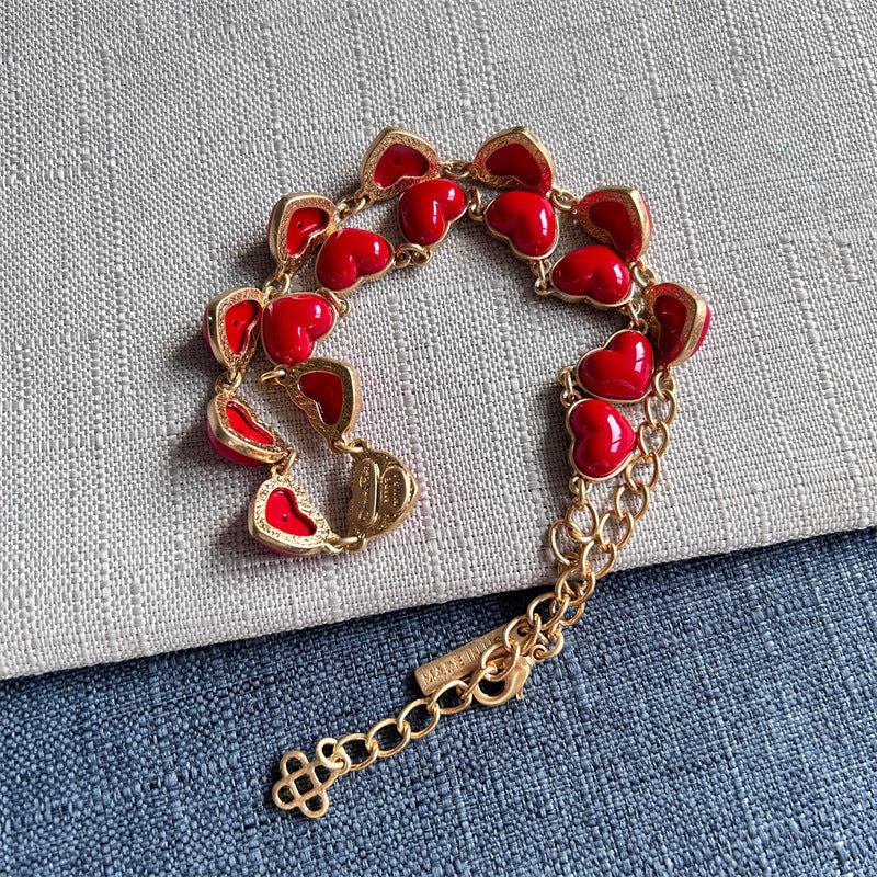 Red heart-shaped necklace with gold chain, heart charms, and tag extender
