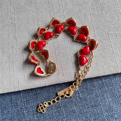 Red heart-shaped necklace with gold chain, heart charms, and tag extender