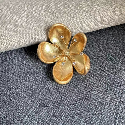 Gold-tone cherry blossom metal brooch with petal texture and rhinestone center accents