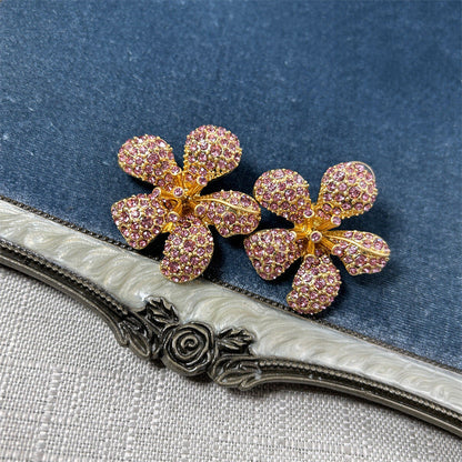 Five-petal flower stud earrings with pink crystal stones on gold-tone setting