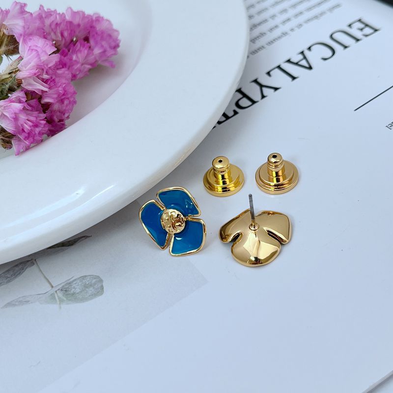 Tory Burch enamel camellia stud earrings with blue petals; gold posts visible