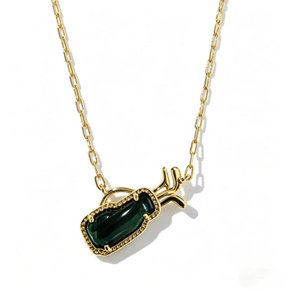 Gold-tone necklace close-up with green gem-like rectangular pendant and side horn accents