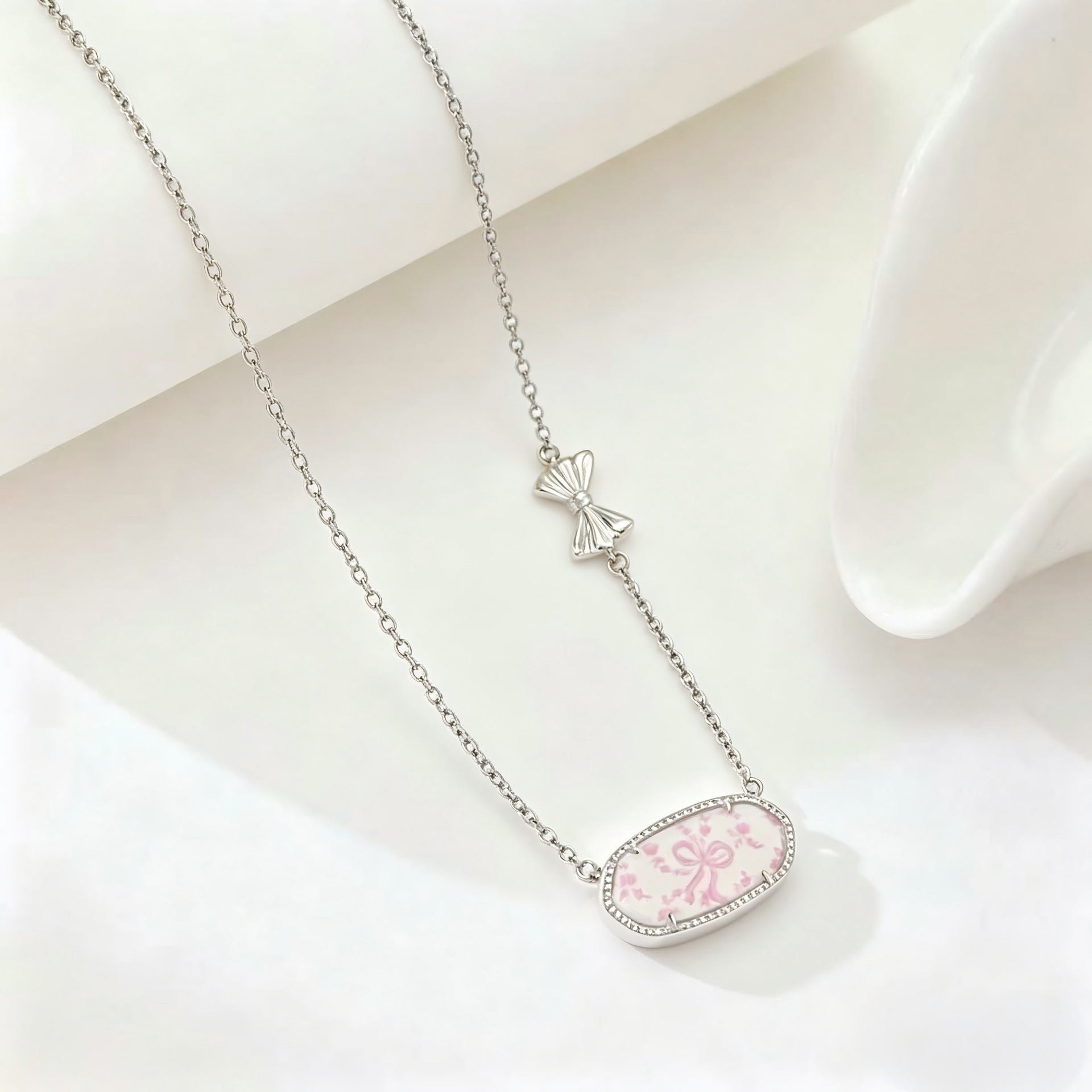 Silver-tone bow charm oval pendant necklace with pink floral enamel