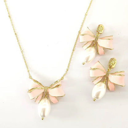 Gold bow pendant necklace with pink enamel ribbon and pearl, plus matching stud earrings