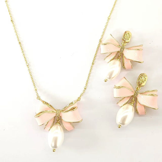 Gold bow pendant necklace with pink enamel ribbon and pearl, plus matching stud earrings