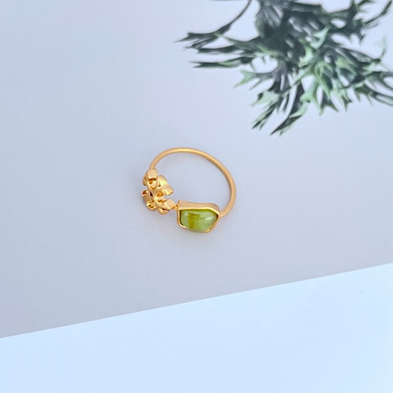 Gold-tone matte logo ring with green acrylic stone and ornate logo setting
