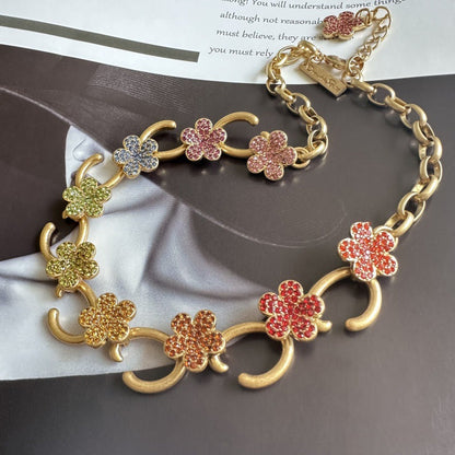 Gold-plated floral pendant necklace with pink, red, and yellow rhinestone clover charms
