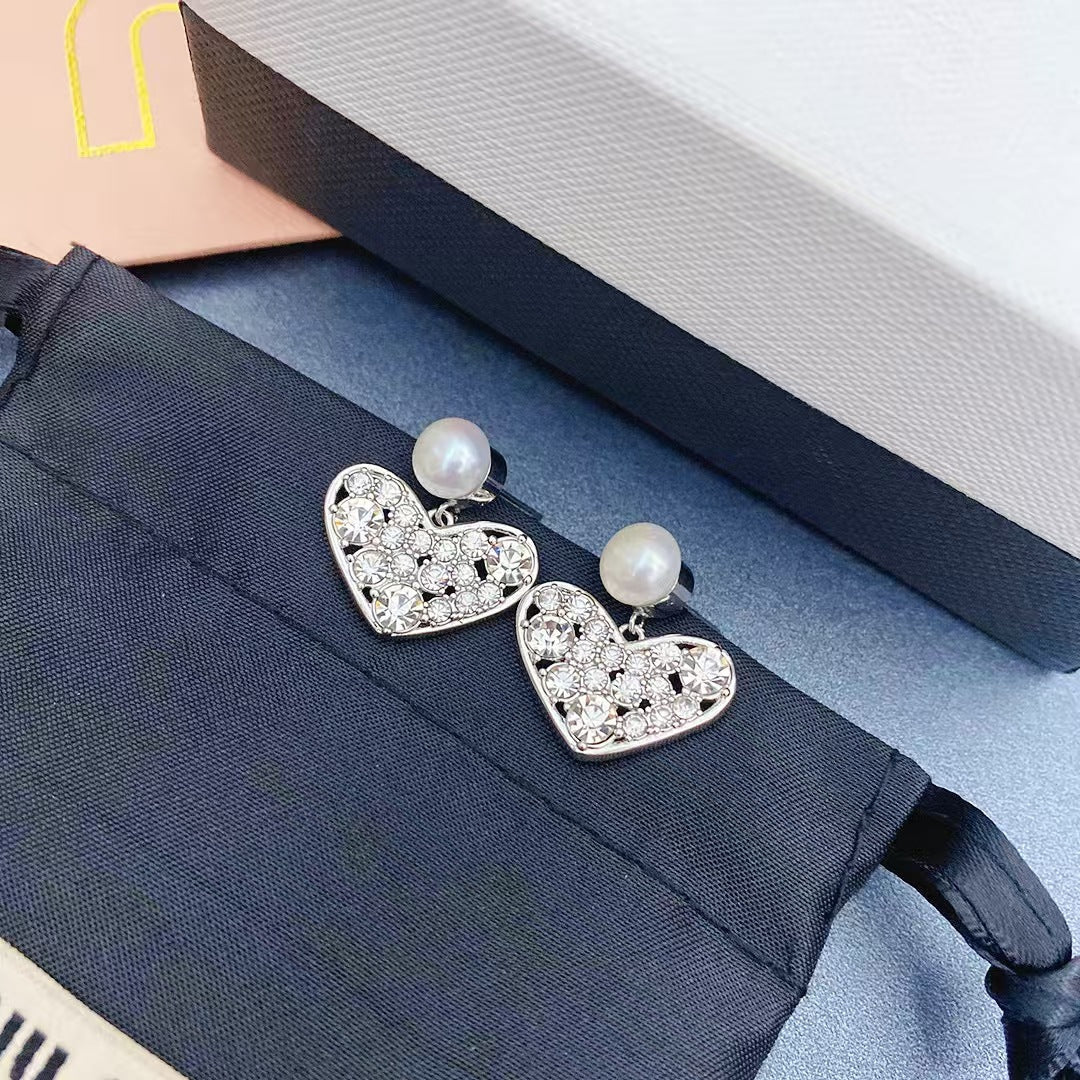Heart-shaped pearl stud earrings with rhinestone crystal details, white gold setting