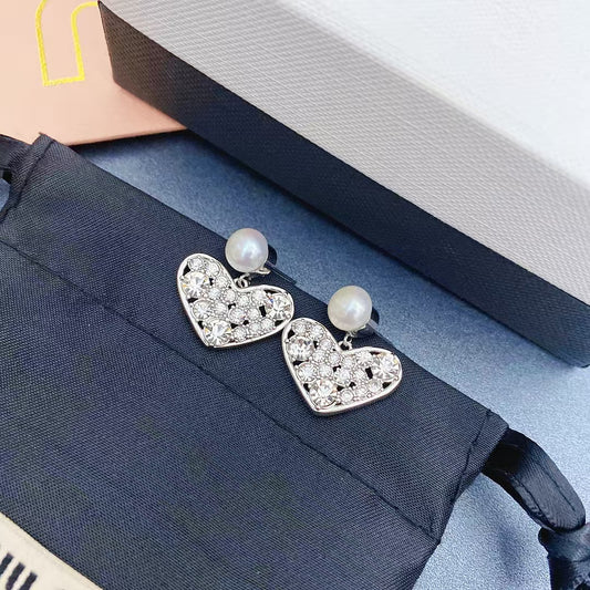 Heart-shaped pearl stud earrings with rhinestone crystal details, white gold setting