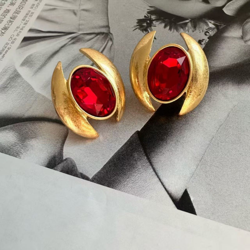 Gold-tone oval crystal stud earrings with red faceted stones