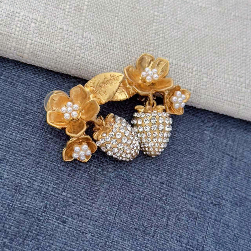 Gold-tone clip-on earrings with layered pearl flower accents and rhinestone strawberry drops