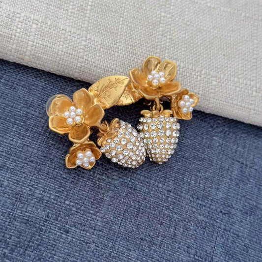 Gold-tone clip-on earrings with layered pearl flower accents and rhinestone strawberry drops
