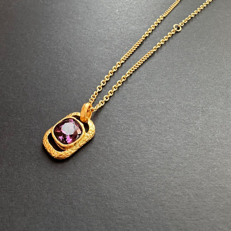 Gold-tone hammered square pendant necklace with purple faceted gemstone on chain