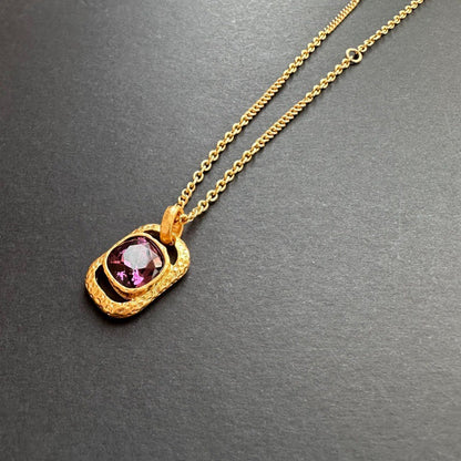 Gold-tone hammered square pendant necklace with purple faceted gemstone on chain