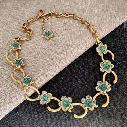 Gold-plated floral pendant necklace with teal rhinestone clover charms and curved links