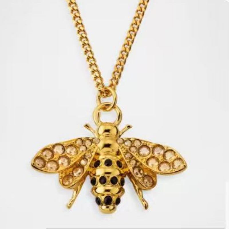 Gold bee pendant necklace with round stone details on wings and body, hinged clasp loop
