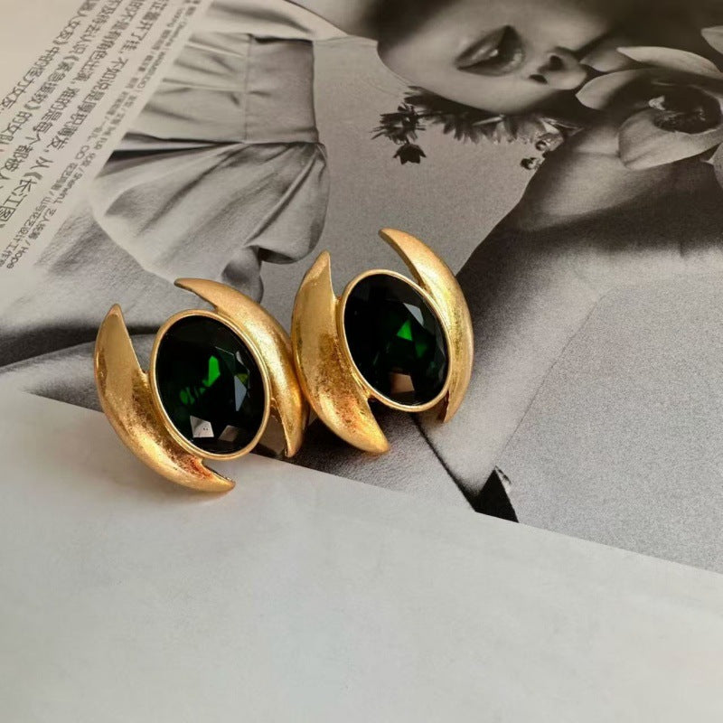Oval crystal stud earrings with dark green gem and gold-tone crescent claws