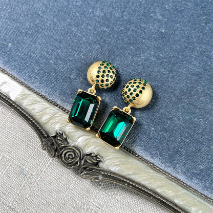 Gold-tone stud earrings with green square-cut drop stones and round jeweled caps