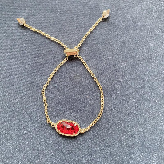 Gold-tone chain bracelet with oval red gemstone pendant and square top clasp links