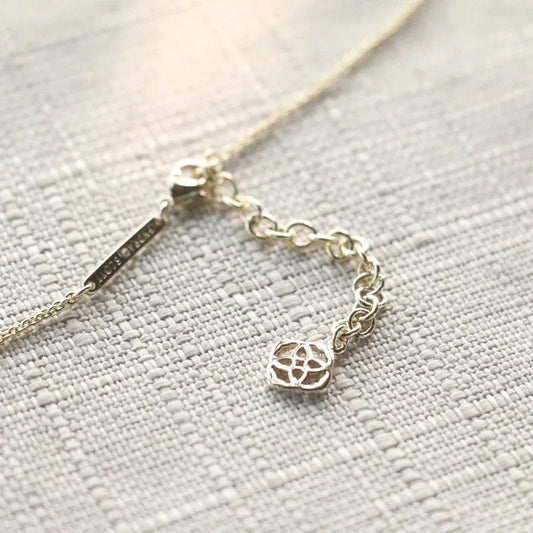 Gold-tone pendant necklace chain with round charm, close-up
