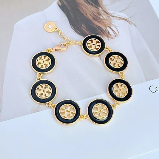 Round enamel bracelet with black circular charms, gold-tone chain and toggle clasp