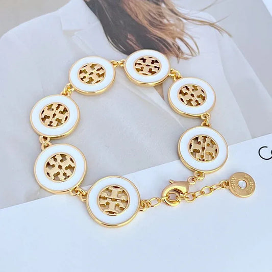 Round enamel bracelet with white circular charms, gold-tone links and toggle clasp
