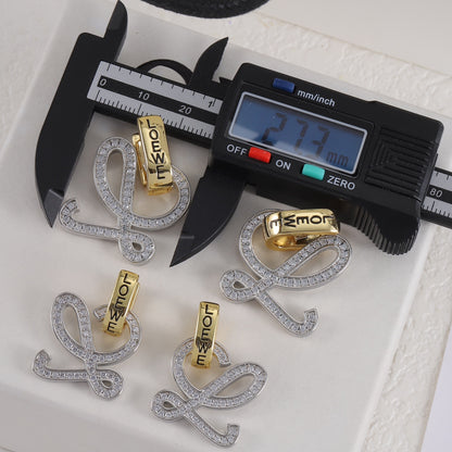Gold and silver logo stud earrings with openwork outline and clear stones; digital caliper shown