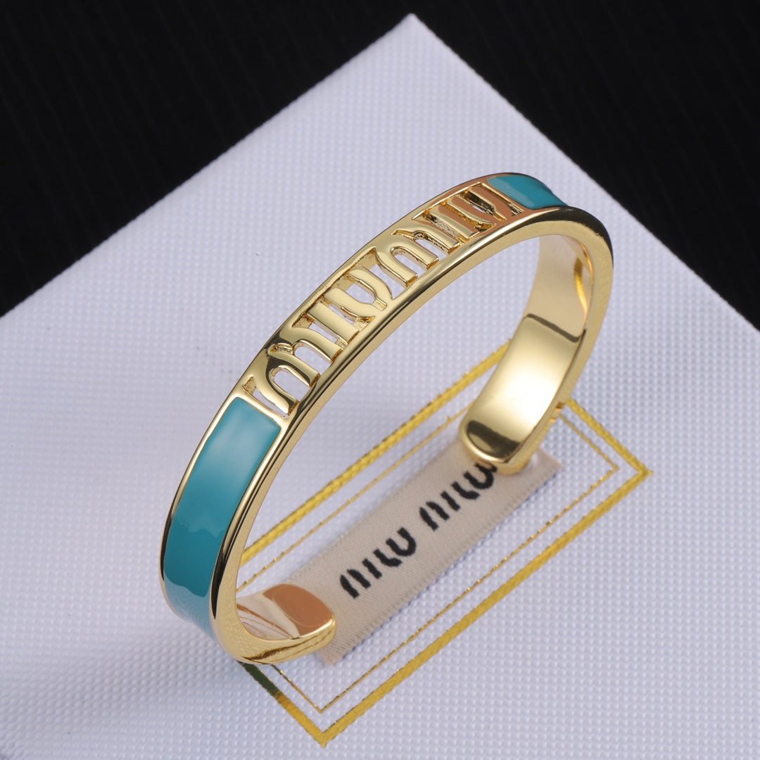 Enamel openwork logo bangle, gold-tone cuff with teal enamel panel and cutout lettering