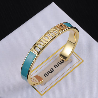 Enamel openwork logo bangle, gold-tone cuff with teal enamel panel and cutout lettering