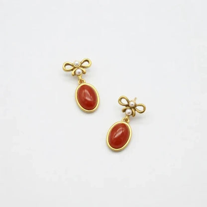 Vintage red oval glass stud earrings with gold bow top and small pearl accents