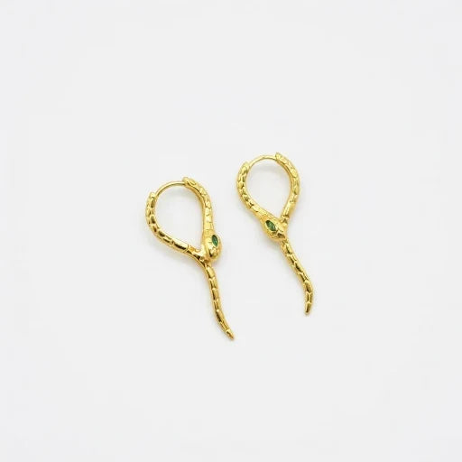 Gold-tone snake ear cuffs with green crystal accents and curved dangling ends