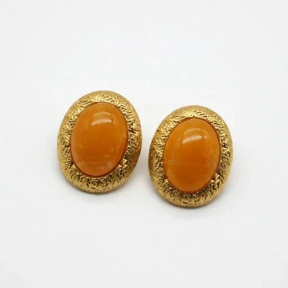 Pair of gold-tone oval stud earrings with glossy yellow glass cabochon and textured rim