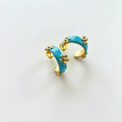 Blue enamel C hoop earrings with small raised flower embellishments in gold tone