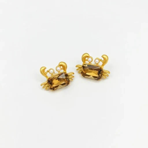 Crab-shaped crystal stud earrings with gold-tone settings, pearls, and a brown gem