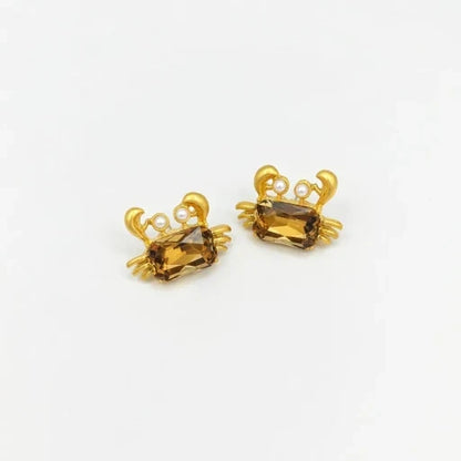 Crab-shaped crystal stud earrings with gold-tone settings, pearls, and a brown gem