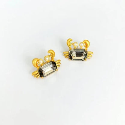 Crab-shaped crystal stud earrings with gold-tone settings, pearls, and a dark smoky gem