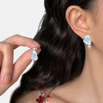 Asymmetric blue enamel drop earrings with white pearl accents and silver-tone backs